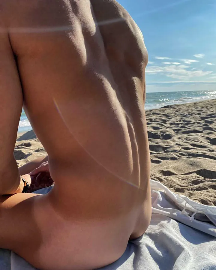 Homme torse nu, en sous-vêtements, debout près d'une fenêtre, regardant vers l'appareil photo, dans une ambiance naturelle et douce.