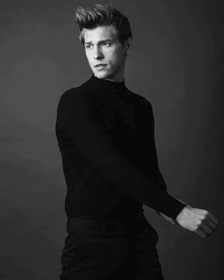 Homme torse nu, en sous-vêtements, debout près d'une fenêtre, regardant vers l'appareil photo, dans une ambiance naturelle et douce.