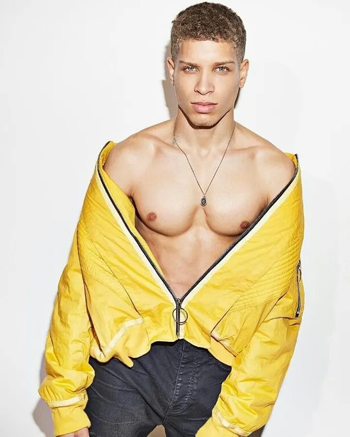 Homme torse nu, en sous-vêtements, debout près d'une fenêtre, regardant vers l'appareil photo, dans une ambiance naturelle et douce.