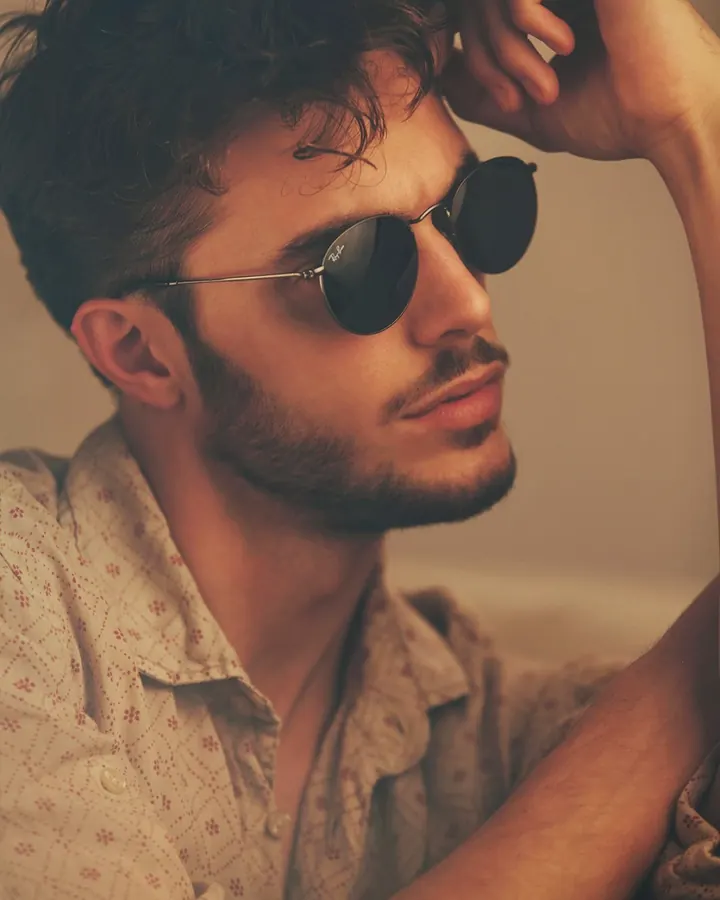Homme torse nu, en sous-vêtements, debout près d'une fenêtre, regardant vers l'appareil photo, dans une ambiance naturelle et douce.