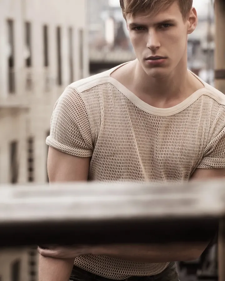Jeune homme blond en chemise blanche, regardant de côté avec une expression sérieuse.