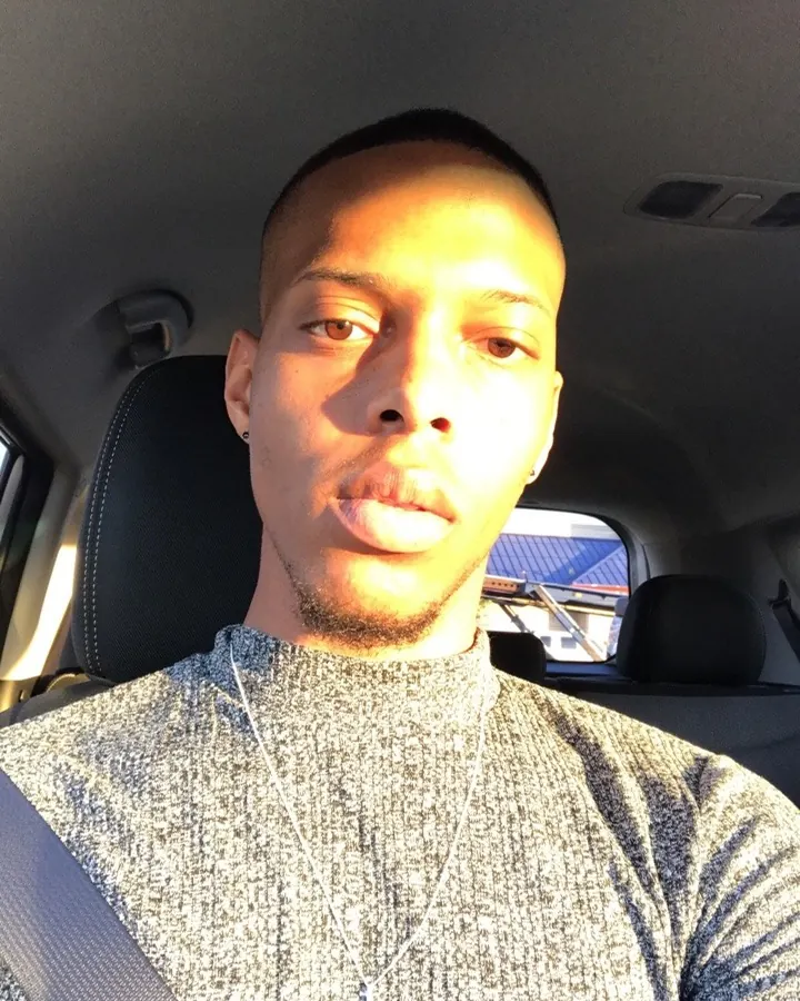 Homme africain en t-shirt gris, assis dans une voiture, regardant vers l'avant