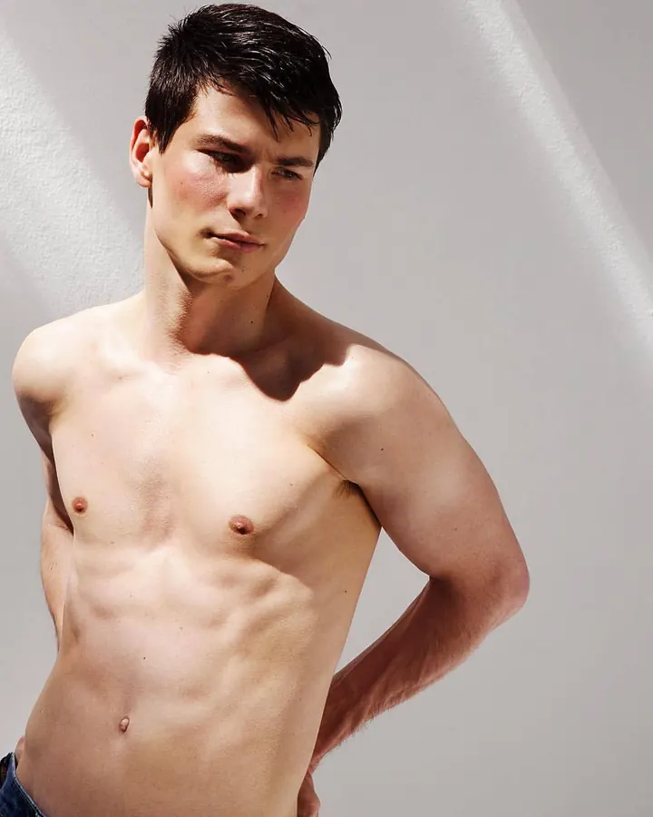 Homme asiatique torse nu, se tenant debout, regardant vers le bas, lumière naturelle
