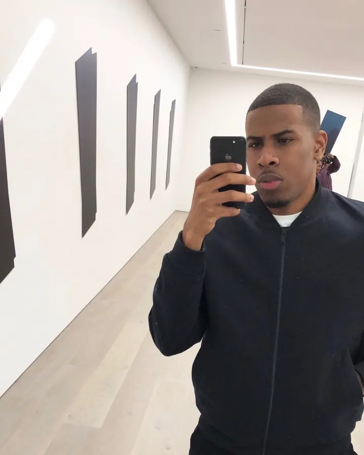 Homme africain portant une veste noire, prenant un selfie dans un musée, regard intense