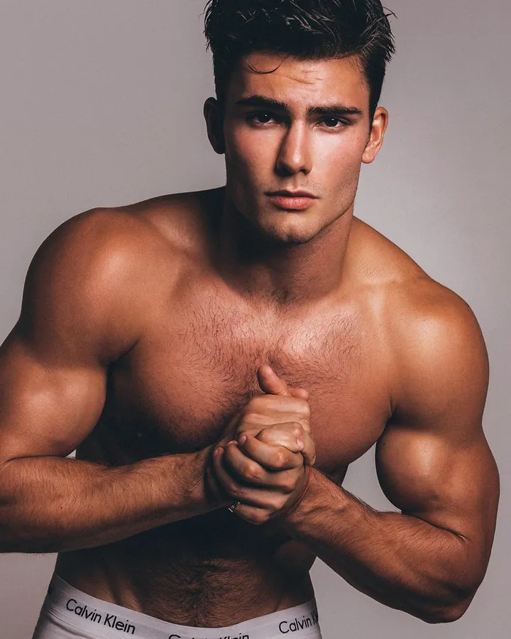 Homme torse nu, debout, regardant directement l'appareil photo, avec une main sur la hanche.