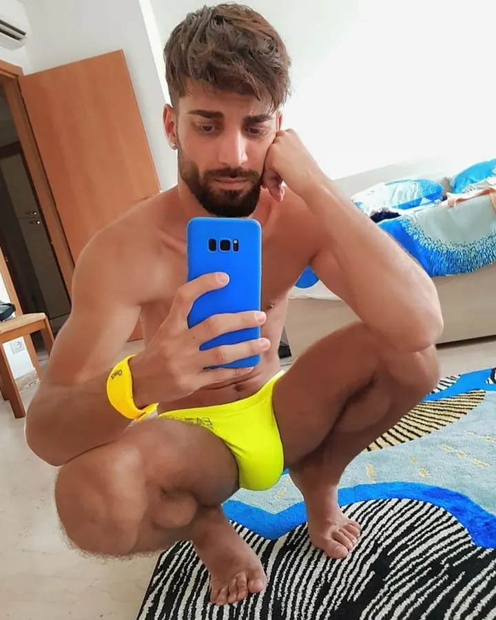 Homme torse nu, debout, regardant directement l'appareil photo, avec une main sur la hanche.